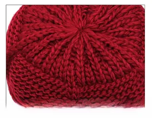 Macro shot of red knitted hat top showing detailed stitching and thick wool texture