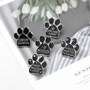 Set of 5 enamel dog paw pins with pet love slogans on a stylish fabric background