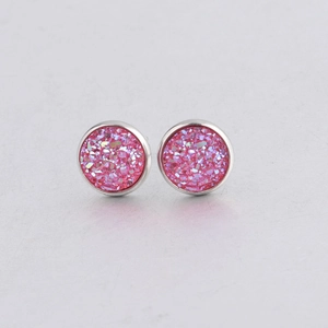 Macro detail of 10mm pink glitter stud earrings with silver-tone stainless steel edges