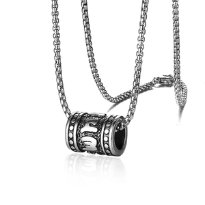 Macro detail of silver titanium steel cylinder pendant with engraved box chain textures