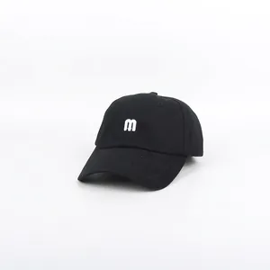 Close-up of white embroidered letter m on a premium black cotton baseball cap