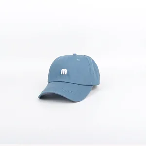 Detail of blue cotton baseball cap featuring high-quality white letter M embroidery