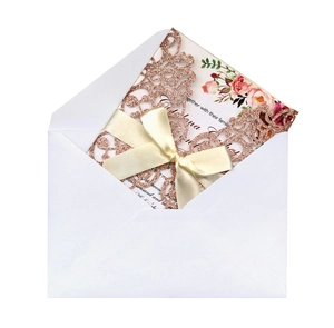 Detailed laser-cut glitter pink wedding invitation with floral insert and cream ribbon