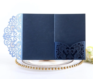 Detail of laser-cut navy blue wedding invitation card on a decorative golden plate