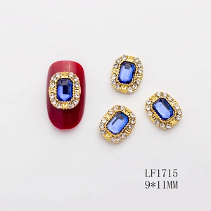 Detalle de joya para uñas con gema azul oscuro y diamantes de imitación en base dorada