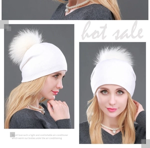 Dettaglio del cappello in maglia bianca con un soffice pompon in finta pelliccia sopra