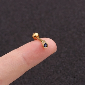 Macro shot of gold teardrop stud earring with dark blue zircon and threaded backing