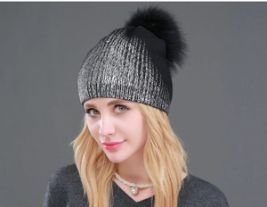 Close-up of black and silver metallic knit winter hat with a fluffy faux fur pompom