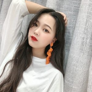 Close-up of vibrant orange long petal tassel earrings worn by a model for a stylish look