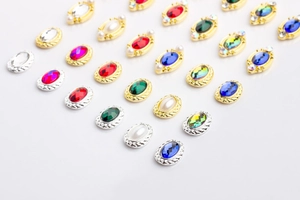 Macro shot of oval gemstone nail art charms with rope textured gold and silver metal frames