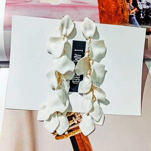 Macro detail of cascading white petal drop earrings with elegant golden chain links