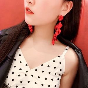 Close-up of red fabric rose petal tassel earrings with elegant gold accents on a model