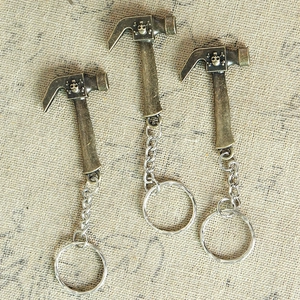 Three bronze vintage hammer keychains featuring small skull patterns on a textured fabric