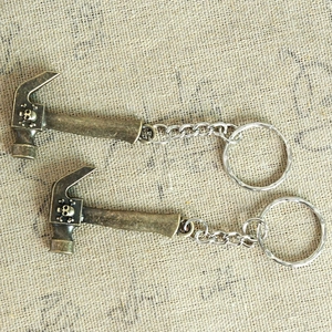 Detail of bronze metal skull hammer keychain pendants on a rustic burlap surface