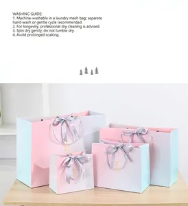 Detail of four gradient pink and blue paper gift bags with satin bows on a wooden table