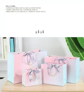 Detail of four gradient pink and blue paper gift bags with satin bows on a wooden table