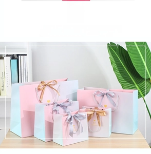 Detailed set of gradient pink and blue paper gift bags with silk bow handles and gold foil