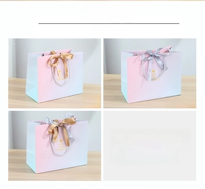 Detail of gradient gift bags showing gold and silver ribbon handle options on wood surface