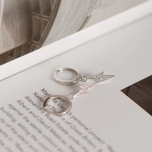 Macro shot of silver lightning bolt earrings with pavé cubic zirconia on magazine background