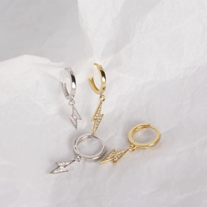 Macro shot of silver and gold lightning bolt hoop earrings with clear cubic zirconia stones