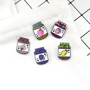 Macro view of colorful fruit jam jar enamel pins with glitter on a white canvas bag