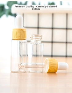 Three transparent glass dropper bottles with wood grain caps on a wooden tabletop