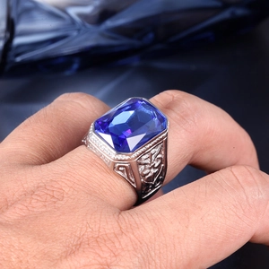 Macro shot of men's silver ring featuring a large rectangular blue gemstone and side engravings