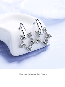Macro shot of silver wreath earrings with sparkling crystals on white ceramic stand