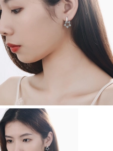 Macro shot of silver flower earrings with sparkling crystals worn by a female model