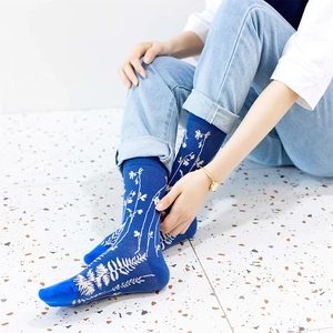 Navy blue crew socks with white leaf pattern on model for outdoor lifestyle look
