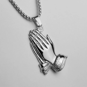 Close-up of silver praying hands pendant with polished finish on a box chain