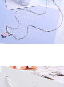 Macro shot of silver branch necklace featuring pink cherry blossom petals and extender chain