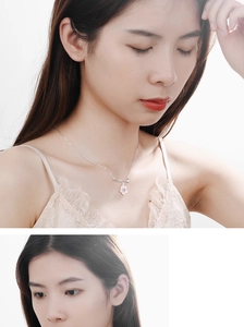 Close-up of pink cherry blossom pendant with silver chain worn on a female neck