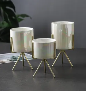 Three pearlized ceramic vases with gold metal tripod stands for minimalist home decor