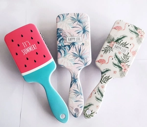 Detailed view of three plastic air cushion hairbrushes with colorful summer themed patterns