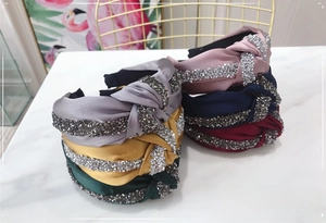 Detail of multi-color knotted satin headbands with sparkling rhinestones on marble surface