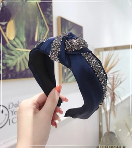 Detail of navy blue knotted headband featuring shimmering grey rhinestones on satin fabric
