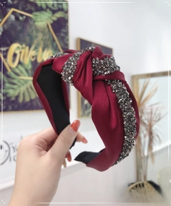 Detail of burgundy knot headband featuring grey rhinestones on a satin textured fabric