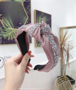 Close-up of pink satin knotted headband with sparkling silver rhinestone trim and nonslip lining