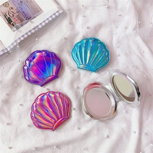 Detailed view of colorful shell-shaped folding makeup mirrors on white pearl fabric