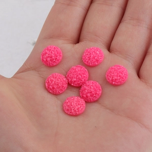 Macro shot of 10mm pink glitter resin druzy cabochons held in hand for size display