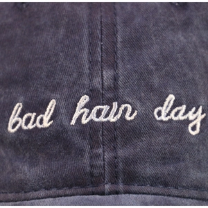 Detailansicht der weißen bad hair day Stickerei auf verwaschener dunkelblauer Baumwollkappe