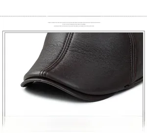 Détail de la casquette d'hiver en cuir marron foncé avec couture rouge contrastée