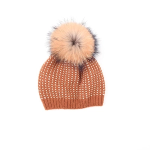 Dettaglio del cappello in maglia per bambini marrone caramello con grande pompon di pelliccia