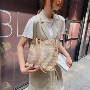 Handmade woven straw tote bag with thin shoulder straps shown on outdoor model