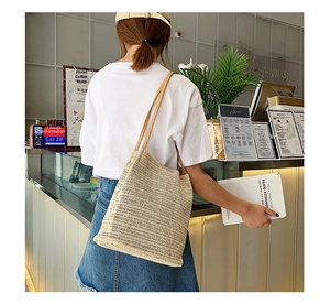 Borsa tote in paglia fatta a mano con cinturini in pelle marrone indossata da modella