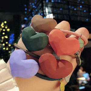 Detailed view of heart-shaped silicone hair ties in five different colors with elastic bands
