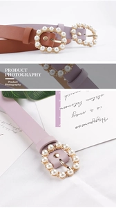 Detail of round pearl buckle on thin leather belts in purple and brown colors