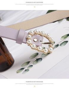 Detailed close-up of a purple leather belt featuring a round pearl-studded metal buckle