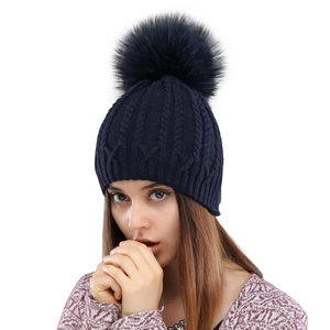 Navy blue winter knitted cable hat for women with a fluffy faux fur pompom decoration